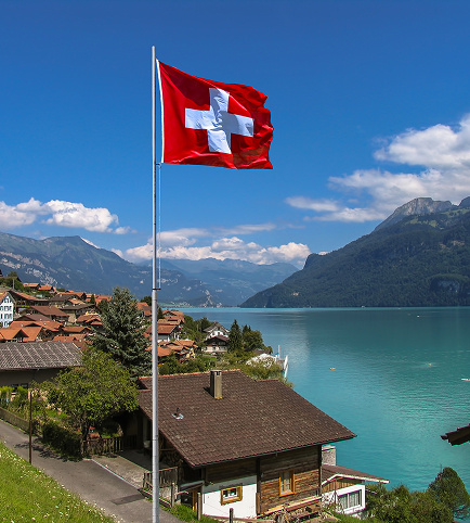 Swiss flag against a mountain panorama and lake, symbolic image for Dr. Hartmann Chemietechnik Switzerland